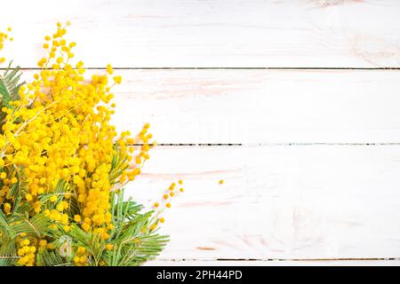 Mimosa fiori bouquet sullo sfondo rustico bianco legno. Decorazioni in stile elegante e shabby con fiori. Messa a fuoco selettiva. Spazio per il testo Foto Stock