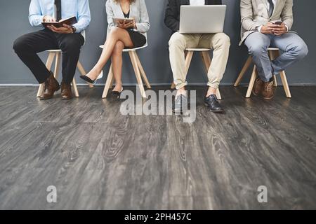 Preparandosi a mettere il loro piede migliore in avanti. Un gruppo di uomini d'affari irriconoscibili che aspettano in fila per un colloquio di lavoro. Foto Stock