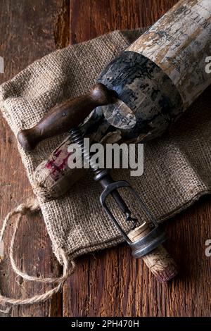 vecchia bottiglia di vino rosso con cavatappi su fondo in legno Foto Stock