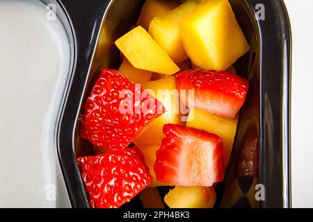 Porzione di dessert allo yogurt con fragola e mango in una tazza di plastica. Foto di alta qualità. Primo piano. Foto Stock