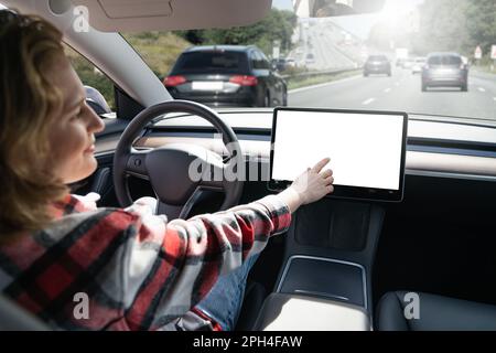 Donna che tocca il display mentre la sua auto è guidata da un autopilota. Schermo bianco. Foto di alta qualità Foto Stock