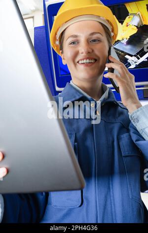 Donna ingegnere con tablet e telefono digitale in una fabbrica intelligente. Primo piano. Foto di alta qualità Foto Stock