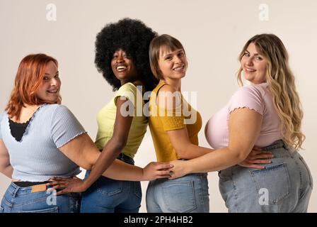 Quattro donne diverse e fiduciose di diverse nazionalità e tipi di corpo sorridendo la fotocamera e irradiando positività. Positività corporea e femminismo Foto Stock