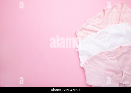 Vestiti per neonati su sfondo rosa Foto Stock