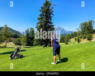 Golfista che si appresta a vedere la montagna e la Luna in una soleggiata giornata estiva a Burgenstock, Nidwalden, Svizzera. Foto Stock