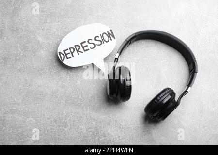 Cuffie e nuvola di voce con parola depressione su tavolo grigio chiaro, piatto Foto Stock