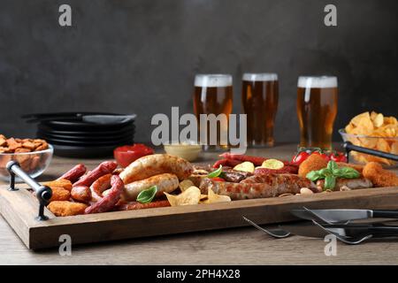 Set di gustosi spuntini e birra diversi sul tavolo di legno Foto Stock