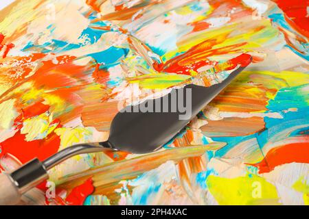Vista in primo piano della tavolozza dell'artista sporca con coltello da pittura come sfondo Foto Stock