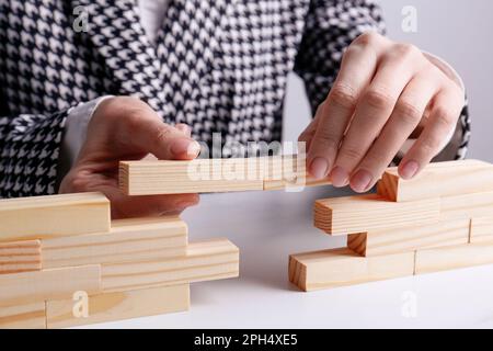 Donna d'affari costruzione ponte con blocchi di legno a tavola, guardaroba. Connessione, relazioni e concetto di trattativa Foto Stock