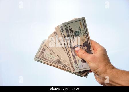 Mano dell'uomo che tiene un mucchio di dollari, su uno sfondo bianco. Foto Stock