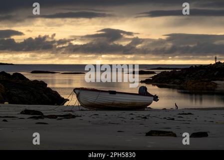 Piccola barca sdraiata sulla spiaggia di Narin/Portnoo al tramonto, County Donegal, Irlanda Foto Stock