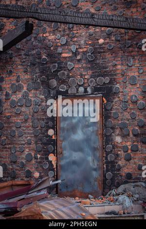 Porta bruciata di casa rovinata. Distrutto edificio dopo l'invasione russa, Ucraina. Guerra in Ucraina. Abbandonata casa danneggiata. Disastro di guerra. Casa decaduta. Foto Stock