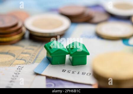 Piccola casa da pile di monete che rappresentano finanziamento casa Foto Stock