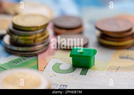 Piccola casa da pile di monete che rappresentano finanziamento casa Foto Stock