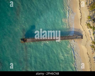 Spiaggia sabbiosa, palme e un molo in legno nel mare. Vista aerea. Giorno d'estate, nessuno è nella foto. Vacanze, resort, nuoto, viaggi in mare. Foto Stock