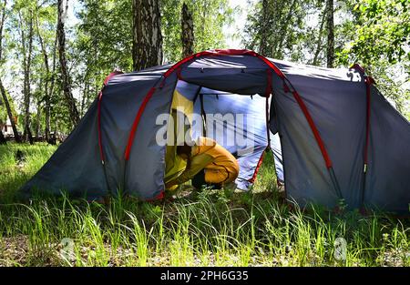 Una ragazza crea una tenda da campeggio durante il suo soggiorno in natura Foto Stock