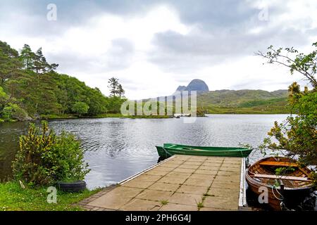 2 barche a remi in legno ormeggiate al molo pavimentato da Glen Canisp Lodge, Loch Druim Suardalain, Assynt, Sutherland, con Suilven che sorge ripidamente sullo sfondo Foto Stock