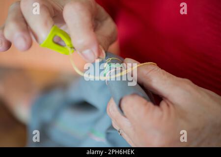 Primo piano delle mani di donna anziana che fanno ricami su un panno. Interno Foto Stock