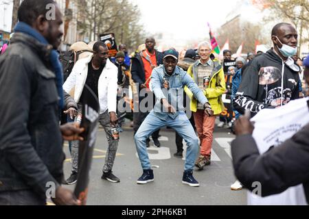 Parigi, Francia. 25th Mar, 2023. I migranti ballano durante una manifestazione contro la legge del Darmanin. Migliaia di migranti francesi e non documentati hanno marciato contro il disegno di legge del ministro degli interni francese Gerald Darmanin, che intende limitare ulteriormente il diritto di asilo, di precarietà e di criminalizzazione degli immigrati e aumentare la quota di manodopera che può essere costretta a lavorare e deportata a volontà. Credit: SOPA Images Limited/Alamy Live News Foto Stock