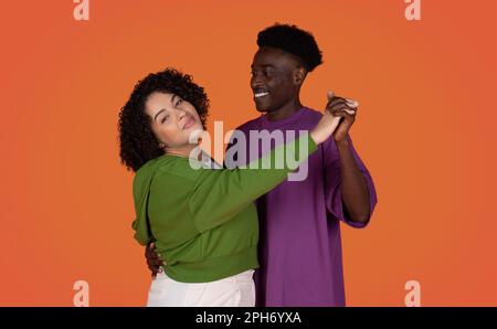 Romantico amore coppia multirazziale ballare su sfondo rosso studio Foto Stock