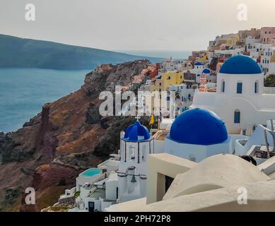 Incredibile panorama serale dell'isola di Santorini. Tramonto estivo sulla famosa località greca di Oia, Grecia. Tradizionali case bianche delle cicladi con tetto blu Foto Stock