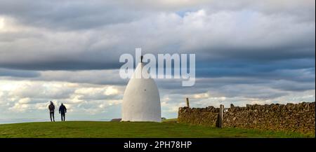 Un paio di escursionisti passeranno accanto a White Nancy, una follia costruita per commemorare la vittoria di Waterloo. La posizione è Kerridge Hill sopra Bollington Foto Stock