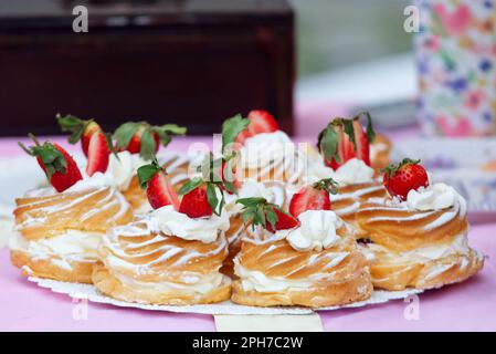 Vassoio pieno di corone con crema di tuorlo e panna montata sul tavolo della pasticceria presso il mercato alimentare di strada degli agricoltori. Primo piano delle corone w Foto Stock