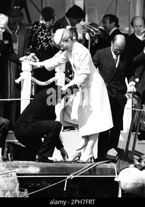 AJAXNETPHOTO. 26TH MARZO, 1982. COWES, INGHILTERRA. - LANCIO DEGLI YACHT AMERICA'S CUP - H.R.H. LA PRINCIPESSA MICHAEL DEL KENT È STATA AIUTATA GRAZIOSAMENTE A RIVA E NELLE SUE SCARPE DOPO UN TOUR A PIEDI NUDI DELLO YACHT CHE AVEVA APPENA CHIAMATO, MENTRE IL BANCHIERE MERCANTILE PETER DE SAVARY (A DESTRA) PROPRIETARIO DELLA VITTORIA FUMA CON I SUOI BROGUES. LA PRINCIPESSA SEMBRA TROVARE DIVERTENTE LA SITUAZIONE DI MR DE SAVARY. FOTO:JONATHAN EASTLAND/AJAX RIF:222904 MX340 17 (VEDERE ANCHE 222904 MX340 18 & 19) Foto Stock