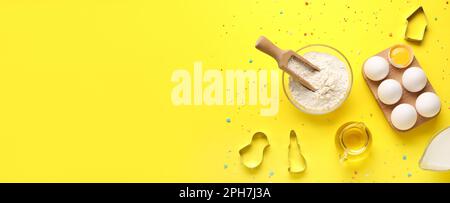 Ingredienti diversi per cuocere i biscotti su sfondo giallo con spazio per il testo Foto Stock