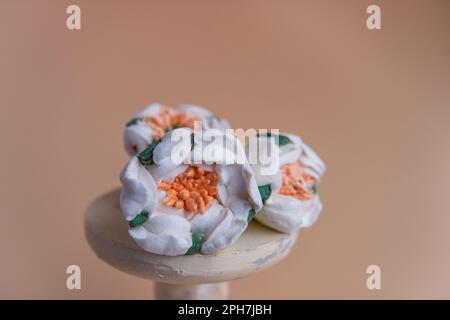 Su fondo rotondo di legno si trovano marshmallows naturali sotto forma di fiori bianchi di camomilla. Dolci senza zucchero. Pasticceria creativa Foto Stock