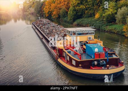 Industria dei trasporti. La chiatta della nave trasporta i rottami metallici e la sabbia con la ghiaia. Chiatta caricata con metallo di scarto è sulla strada. Trasp. Metallo di scarto Foto Stock