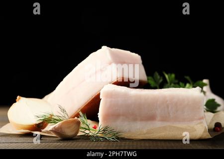 Gustoso maiale salato con erbe, cipolla e aglio su tavola di legno, spicchio Foto Stock