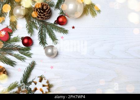 Composizione piatta con rami di abete e decorazioni natalizie su sfondo bianco in legno, spazio per testo. Design del biglietto d'auguri Foto Stock