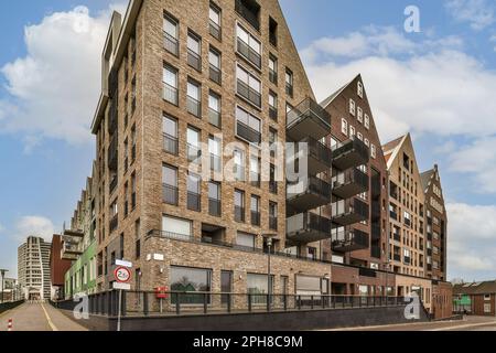 un edificio di appartamenti sul lato di una strada con un cartello di stop di fronte e alcuni edifici dietro Foto Stock