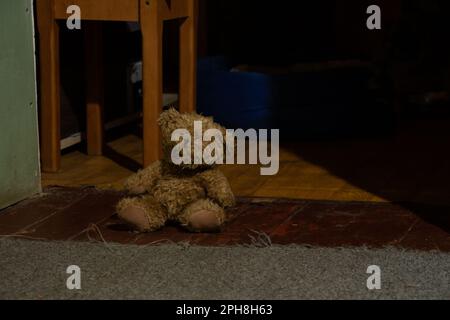 l'orso bruno del teddy del bambino si trova sul pavimento nella stanza nel buio Foto Stock