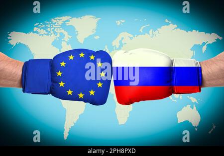Uomini in guanti da boxe con Unione europea e bandiere russe che combattono con la mappa del mondo sullo sfondo, primo piano. Feudo politico Foto Stock