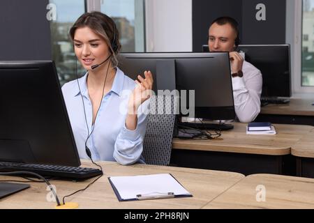 Operatori di contact centre con cuffie che lavorano in uffici moderni Foto Stock