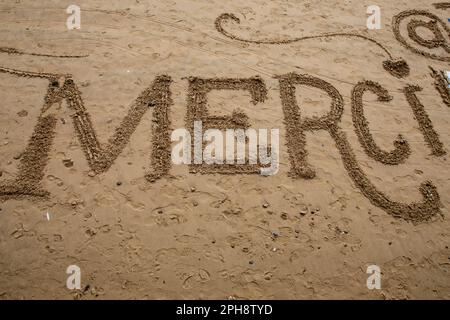 merci segno francese significa grazie testo scritto sulla spiaggia di sabbia Foto Stock