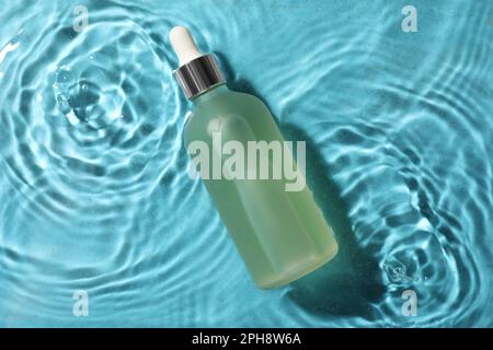 Bottiglia di olio idrofilo in acqua su sfondo azzurro, vista dall'alto Foto Stock