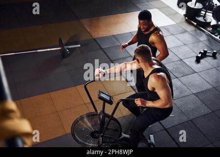 Uomo afroamericano con ragazzo bianco hanno giorno di allenamento in palestra Foto Stock