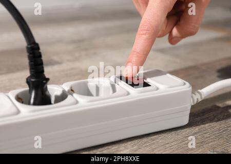 Uomo che preme il pulsante di accensione della prolunga sul pavimento, primo piano Foto Stock