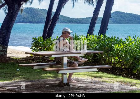 Un uomo Causasiano pensivo che guarda al Mare dei Coralli sulla spianata di Palm Cove, Cairns Northern Beaches, far North Queensland, FNQ, QLD, Australia Foto Stock