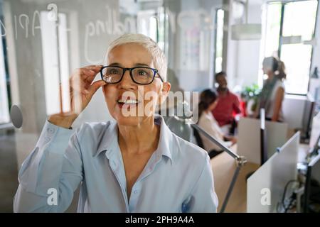 Ritratto di donna matura business sorridere mentre analizzando i processi di lavoro Foto Stock
