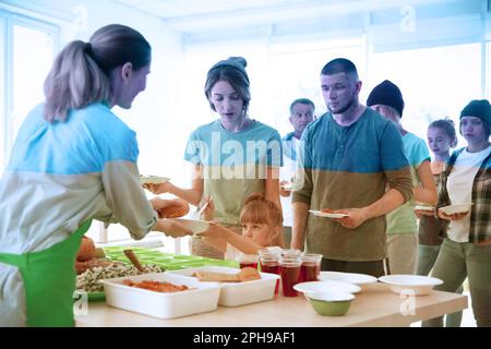 Doppia esposizione di volontari che servono cibo ai rifugiati e bandiera Ucraina. Aiuto durante la guerra Foto Stock