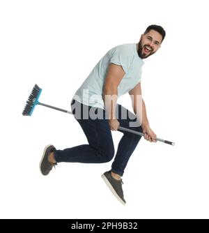 Giovane uomo con scopa che salta su sfondo bianco Foto Stock