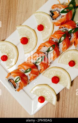 Una varietà di sushi rotolini disposti su un piatto rettangolare, presentati in una composizione esteticamente piacevole Foto Stock