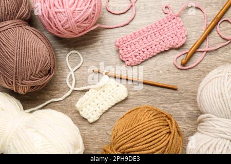 Composizione piana con fili di maglia e ganci a uncinetto su tavola di legno Foto Stock