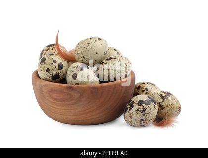 Ciotola di legno, uova di quaglia e piume su fondo bianco Foto Stock