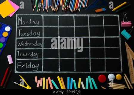 Molti diversi cartoleria e disegnato orario scolastico settimanale su lavagna nera, piatto Foto Stock
