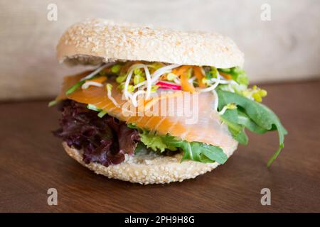 Delizioso sandwich al salmone su pane in bagel. Un bagel è un pane tradizionalmente fatto di farina di grano e di solito ha un buco al centro. Foto Stock